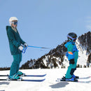Mom helping her child learn to ski using the harness and straps
