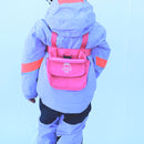 Pink harness on child back showing the pouch and lift handle